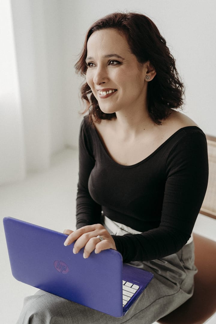 Mulher a sorrir com o computador no colo