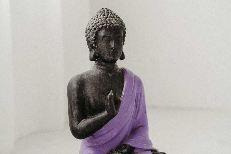 Imagem de buda vestido de roxo em posição de paz e alinhamento.